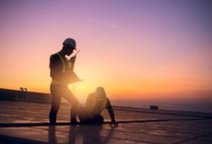 Silhouette of construction workers on a roof at sunset