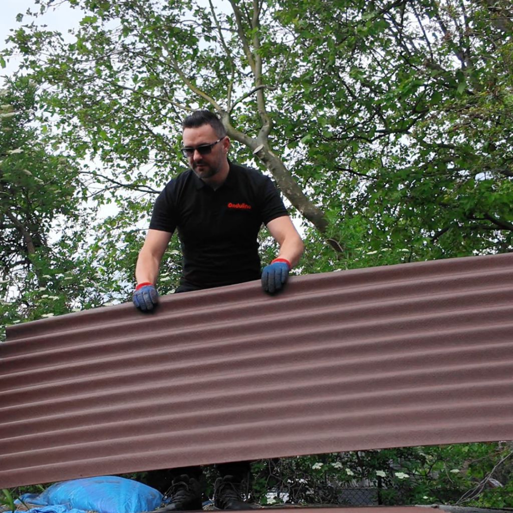 Male worker carries a sheet of metal