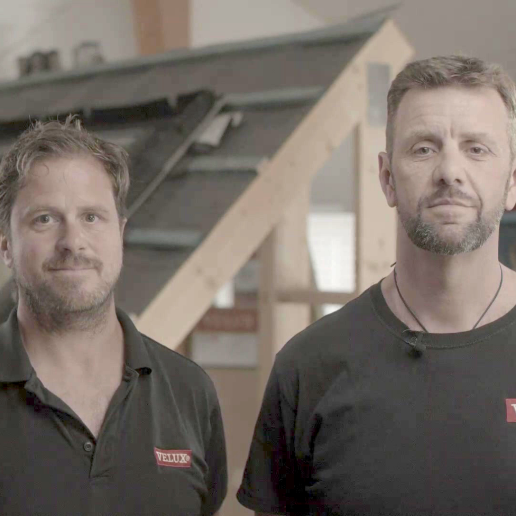 Two men with facial hair in black t-shirts with red logo