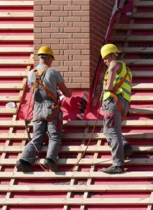 Two male roofers in protective workwear stand on a roof